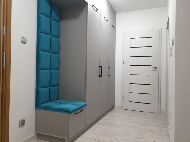 Szafa z wbudowanym pikowanym siedziskiem w stylowym wnętrzu.