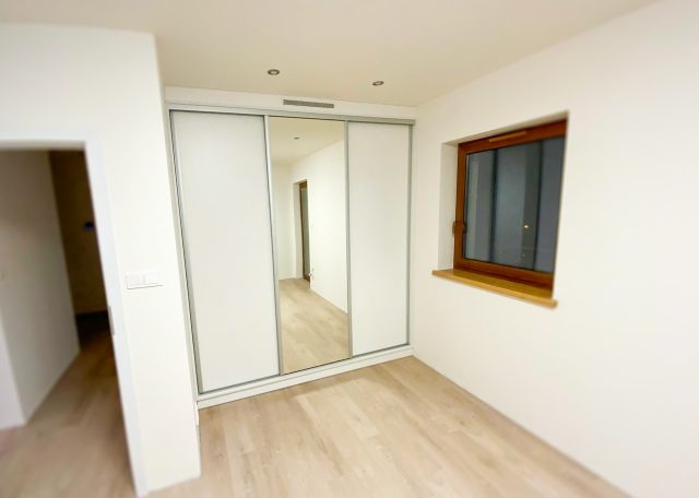 Nowoczesna szafa z przesuwnymi drzwiami w jasnym wnętrzu.