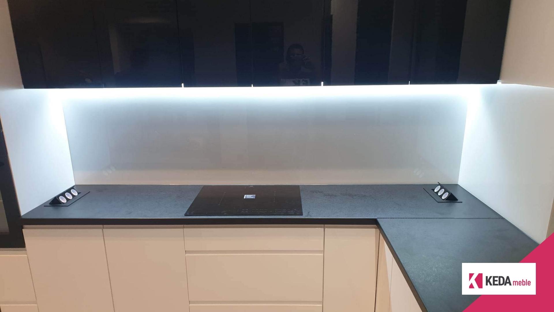 Kuchnia jest sercem domu, miejscem, gdzie rodzinne tradycje łączą się z nowoczesnym designem. W naszej ofercie znajdziesz rozwiązania, które harmonijnie łączą elegancję z funkcjonalnością, tworząc przestrzeń idealną dla każdej rodziny. Szczególnie polecamy biało-czarne kuchnie, które stanowią szczyt elegancji i są praktycznym wyborem dla każdego, kto ceni sobie styl i funkcjonalność w jednym. Elegancja w Kolorach: Biało-Czarne Kuchnie Kombinacja bieli i czerni w kuchni to ponadczasowy wybór, który nigdy nie wychodzi z mody. Białe powierzchnie odbijają światło, sprawiając, że kuchnia wydaje się większa i jaśniejsza. Czarne akcenty dodają z kolei głębi i charakteru, tworząc wyrafinowany kontrast. Duża Przestrzeń Robocza – Klucz do Funkcjonalności Przestronny blat roboczy to podstawa każdej dobrze zaprojektowanej kuchni. Pozwala na swobodną pracę i przygotowywanie posiłków bez zbędnego chaosu. W naszych projektach kładziemy duży nacisk na ergonomiczne rozmieszczenie elementów, aby każda czynność kuchenna była przyjemnością. Listwa LED – Rewolucja w Oświetleniu Kuchennym Odpowiednie oświetlenie to kluczowy element każdej kuchni. Nasze listwy LED nie tylko efektownie prezentują się w przestrzeni, ale także zapewniają doskonałe oświetlenie robocze, które jest niezbędne podczas przygotowywania posiłków. To praktyczne i energooszczędne rozwiązanie, które dodatkowo podkreśla nowoczesny charakter kuchni. Otwarte Półki – Praktyczne i Dekoracyjne Rozwiązanie Otwarte półki w słupku kuchennym to idealne miejsce na przechowywanie butelek wina, oliwy, czy ulubionych kubków do kawy. Dzięki temu Twoje ulubione przedmioty będą zawsze pod ręką, a jednocześnie staną się częścią dekoracji kuchni. Kuchnie na Wymiar – Twój Indywidualny Projekt Dołącz do grona zadowolonych klientów, zamawiając kuchnię na wymiar. Nasze projekty są w pełni dostosowane do potrzeb i oczekiwań każdego klienta. Tworzymy kuchnie, które są nie tylko piękne, ale przede wszystkim praktyczne i funkcjonalne. Podsumowanie Nasze biało-czarne kuchnie to idealne połączenie elegancji i funkcjonalności. Jeśli marzysz o kuchni, która będzie nie tylko piękna, ale także praktyczna i wygodna, zapraszamy do kontaktu. Zrealizujemy dla Ciebie projekt, który spełni wszystkie Twoje oczekiwania.